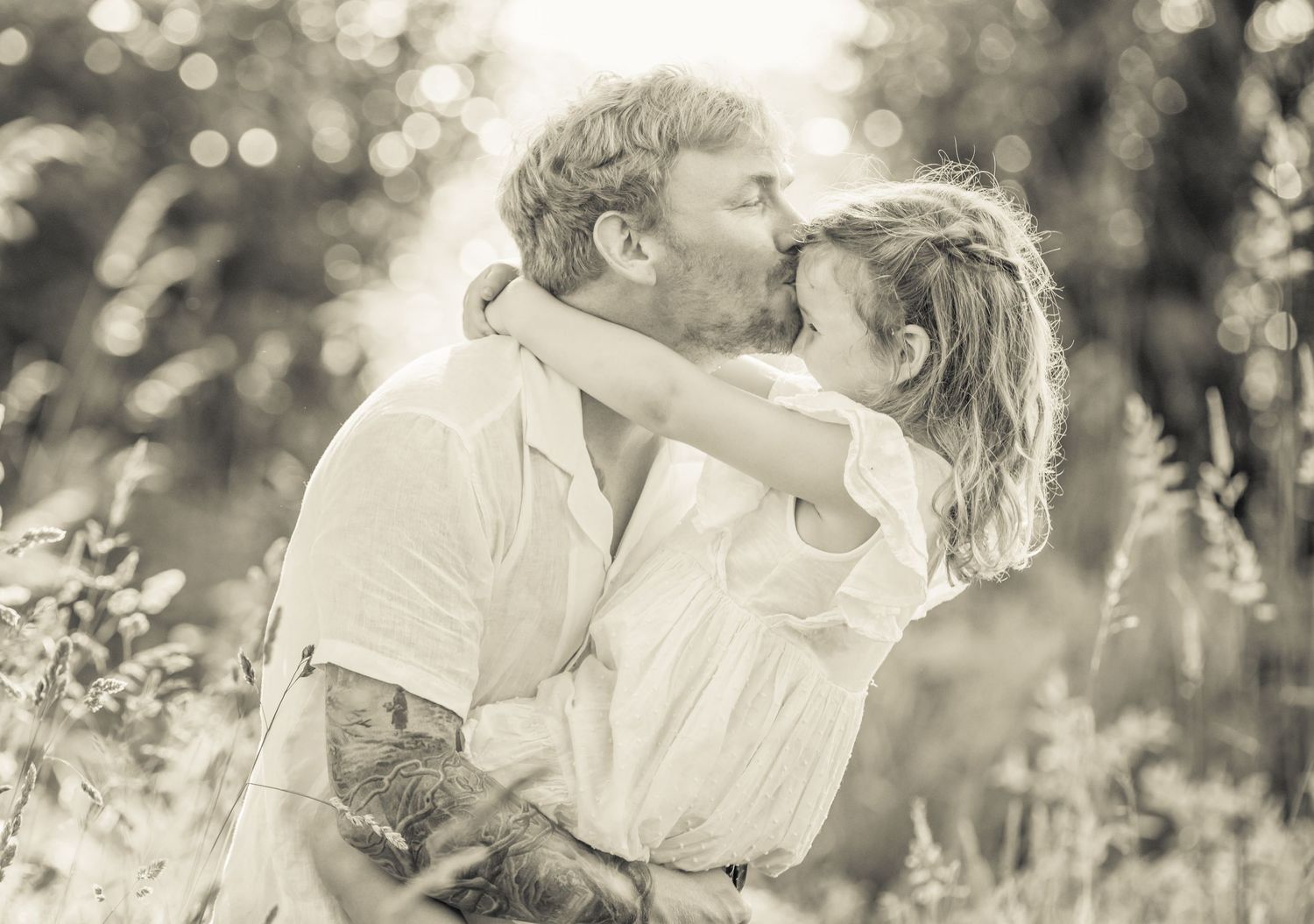 Artistic black and white series capturing tender embraces in a sunlit field.