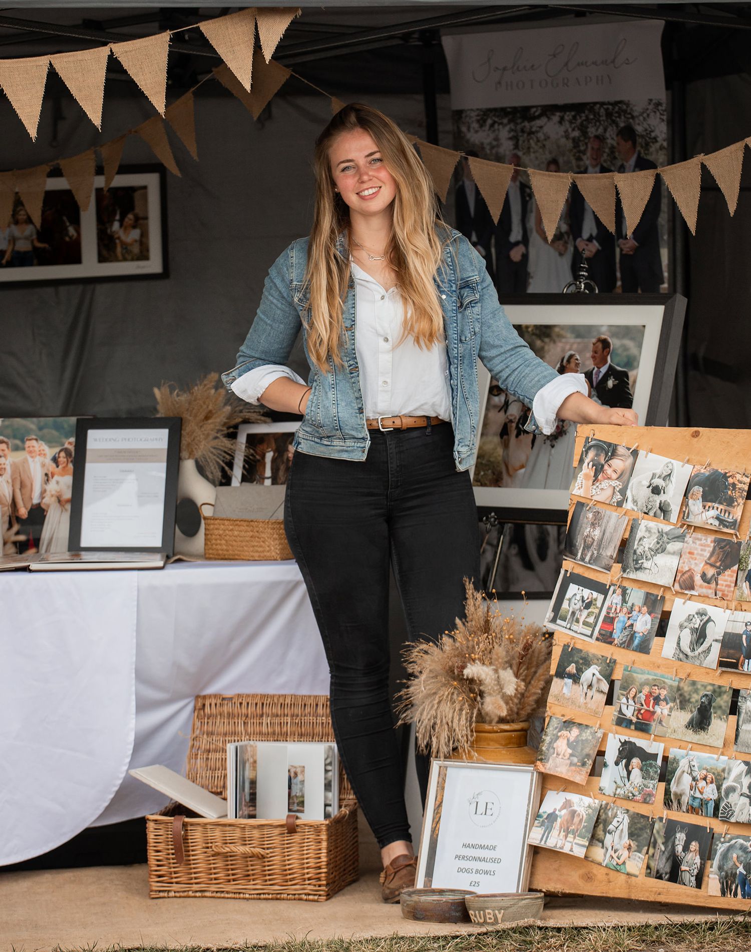 Sophie Edmunds stood in front of her family, equine and wedding photo gallery display with vintage bunting and rustic decor elements.