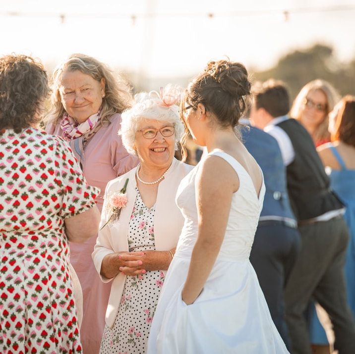 A joyful outdoor gathering at sunset with guests in summer attire mingling and chatting at a social event.