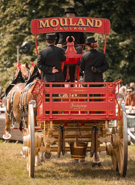 A vintage red Mouland horse-drawn carriage with wooden wheels shown from multiple angles in a grassy field.