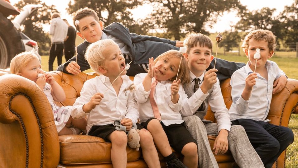 A happy family lounges together on a brown leather couch in a warm, candid moment.