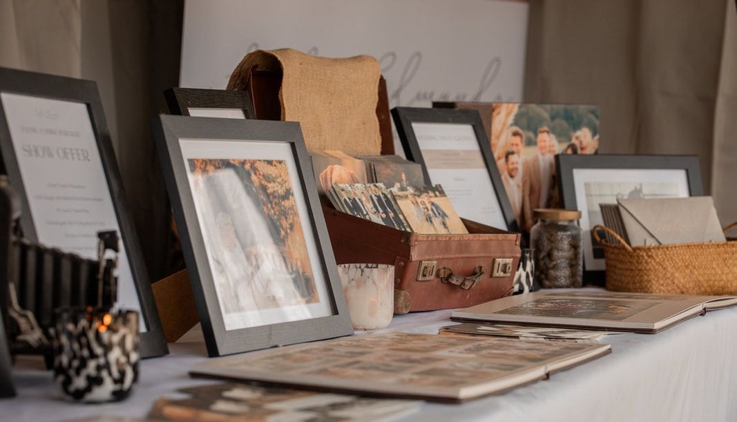 Vintage photographs and frames arranged on a table with brown paper bags and decorative items in muted tones.