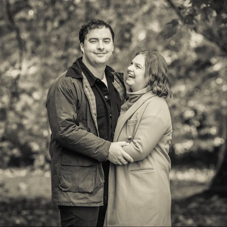 A couple embraces and laughs together outdoors in a candid black and white photo series.
