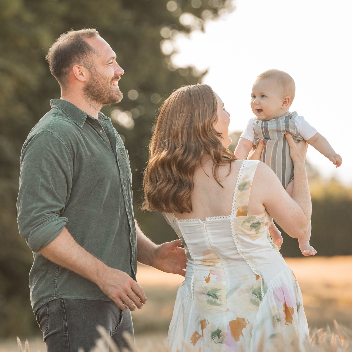 Family enjoying a sunset photoshoot in a field wearing casual attire.