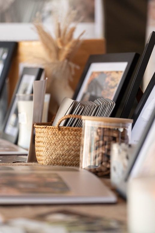 Woven basket organizer and framed photos displayed on a wooden shelf with soft natural lighting and shallow depth of field.