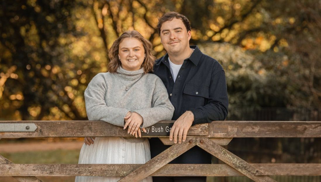 Couple poses together in natural outdoor setting during golden hour sunset for romantic engagement photos.