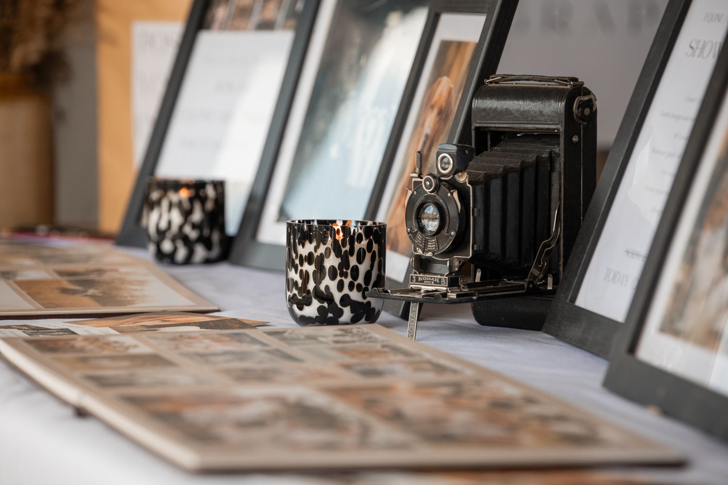 Collection of old cameras and vintage photographs arranged on wooden surface.