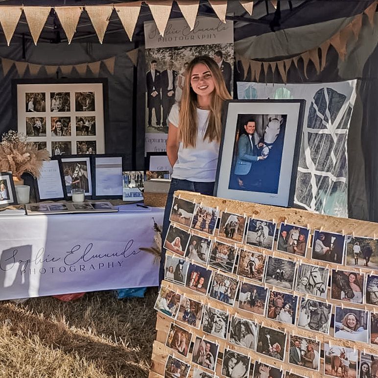 Photography display booth with bunting and multiple photo prints arranged on rustic wooden boards.