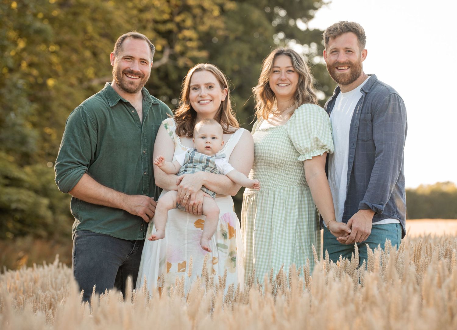 Family portrait session in golden wheat field during sunset.