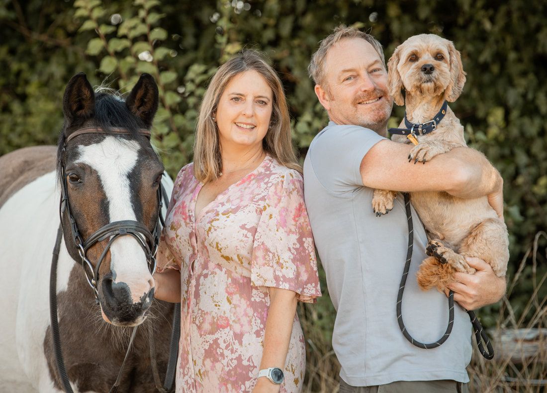 A couple poses outdoors with their small dog and horse in a series of professional portrait photos.