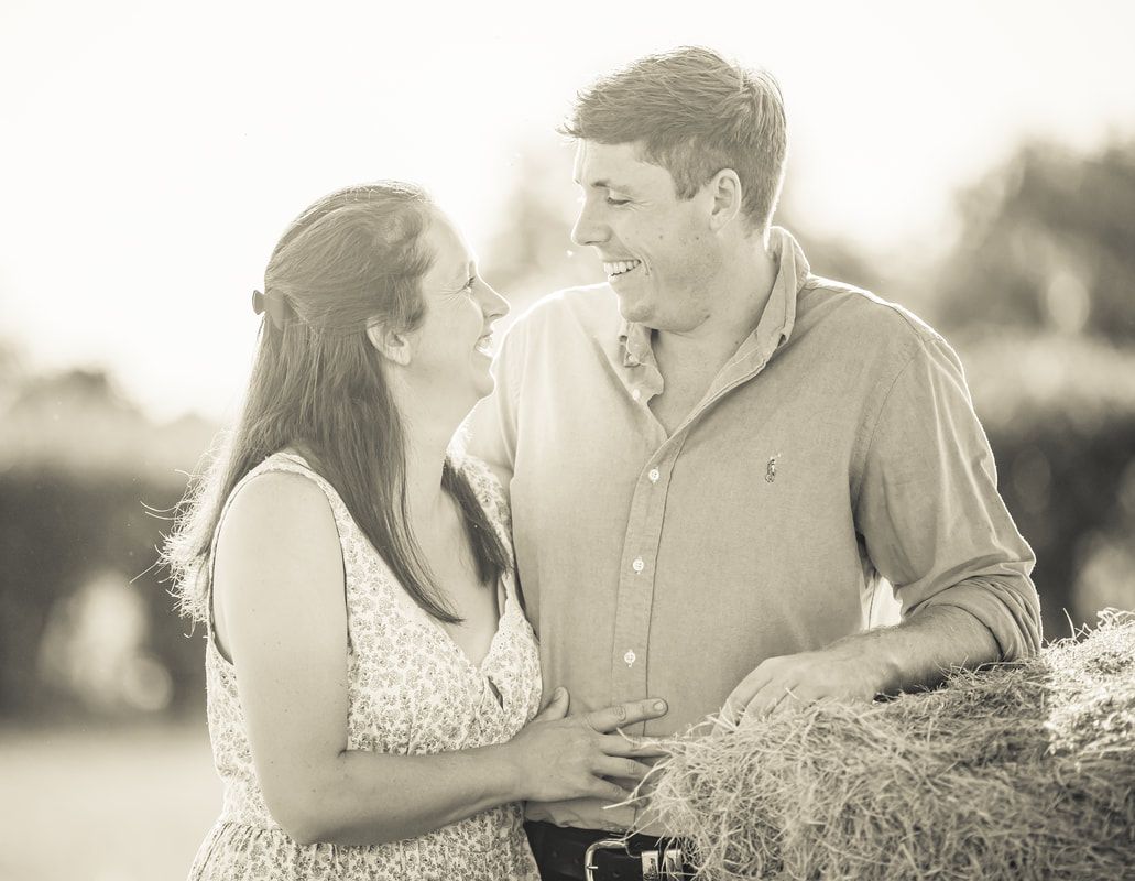 A couple shares intimate moments in a grassy field during a romantic outdoor photo session.