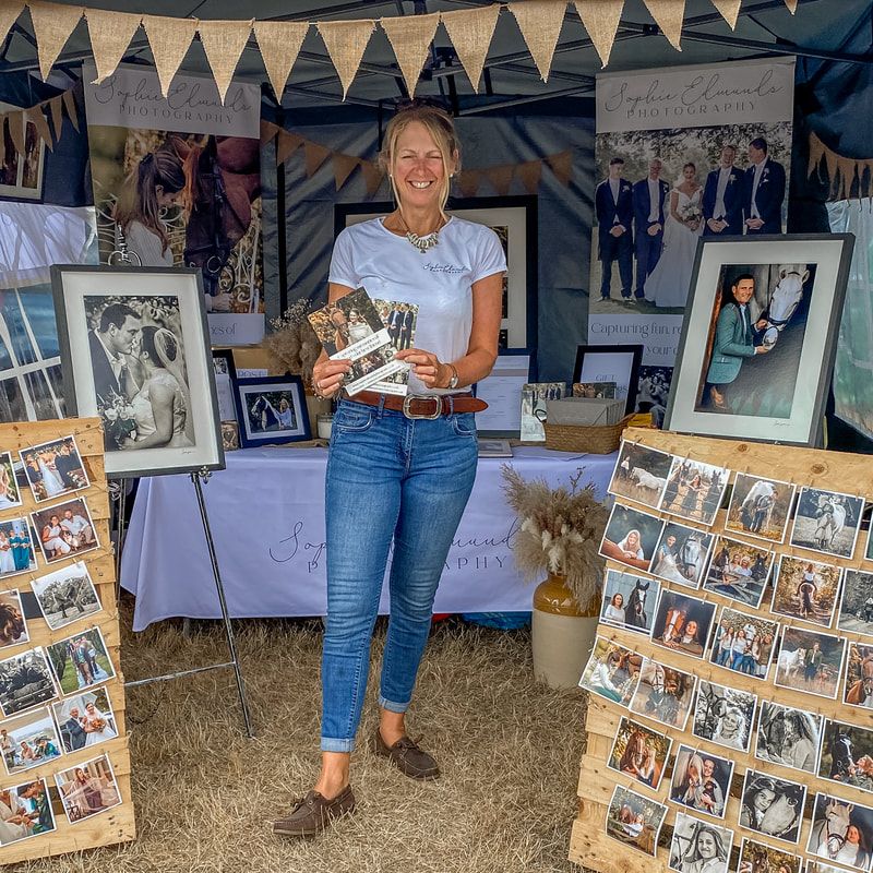 Professional photographer showcasing their portfolio at an outdoor market booth.