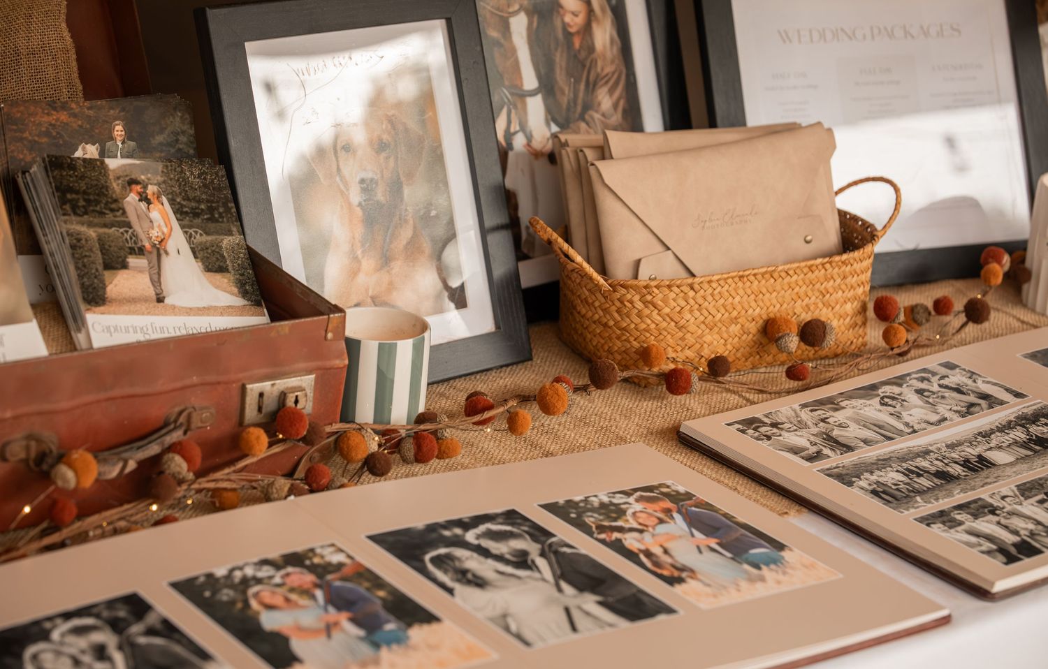 Vintage wedding photos displayed on a table with a wicker basket, autumn berry garland, and framed portraits in warm tones.