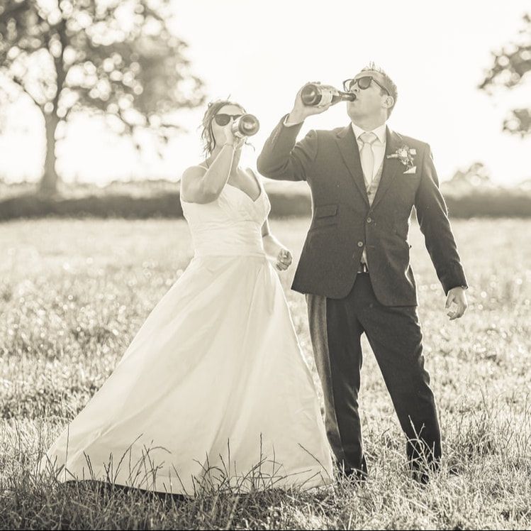 Black and white wedding photo series showing couple dancing joyfully in a sunlit meadow.
