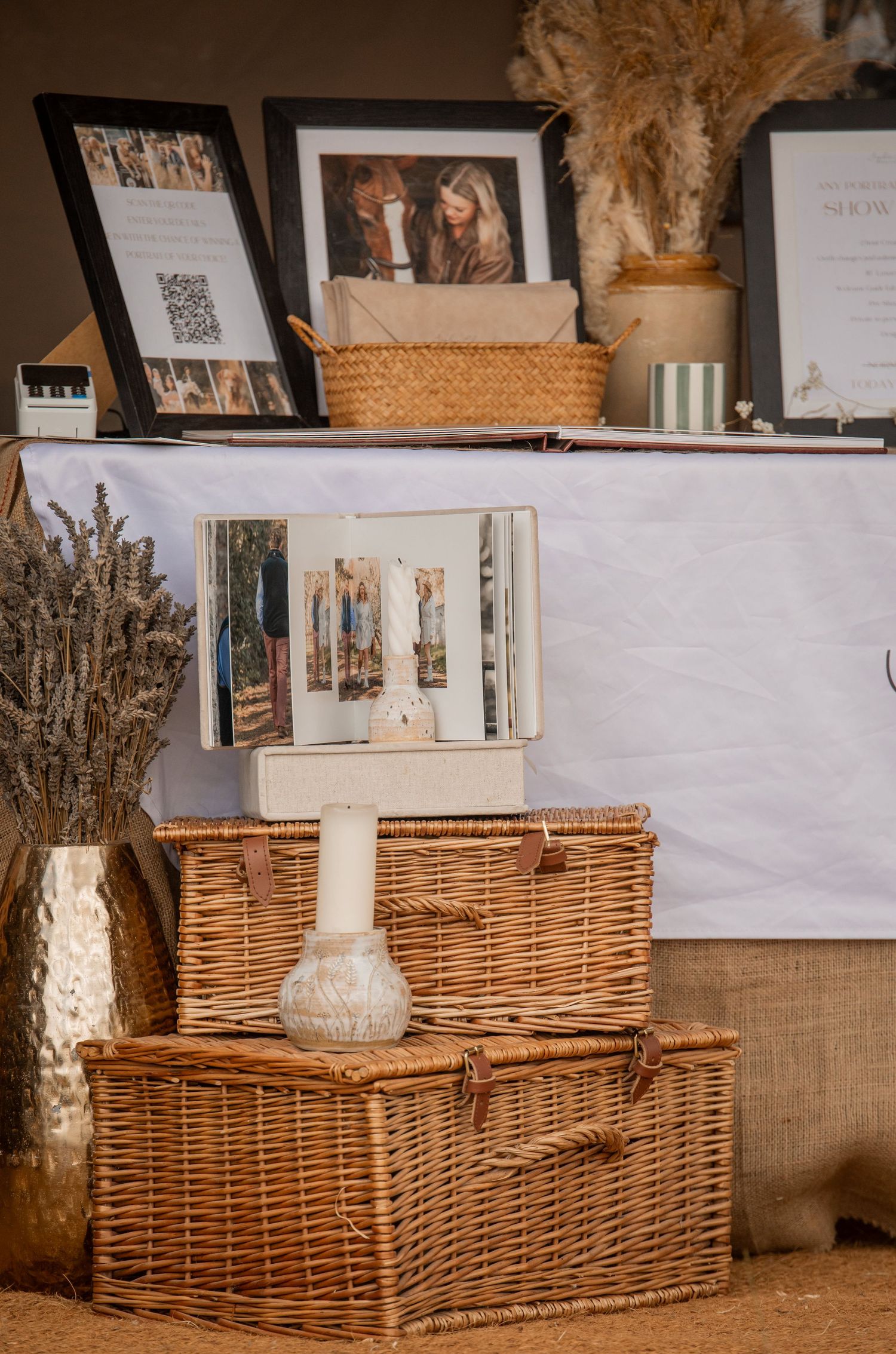 Rustic wicker baskets stacked with framed photos, dried florals, and decorative vases on a elegant display table.