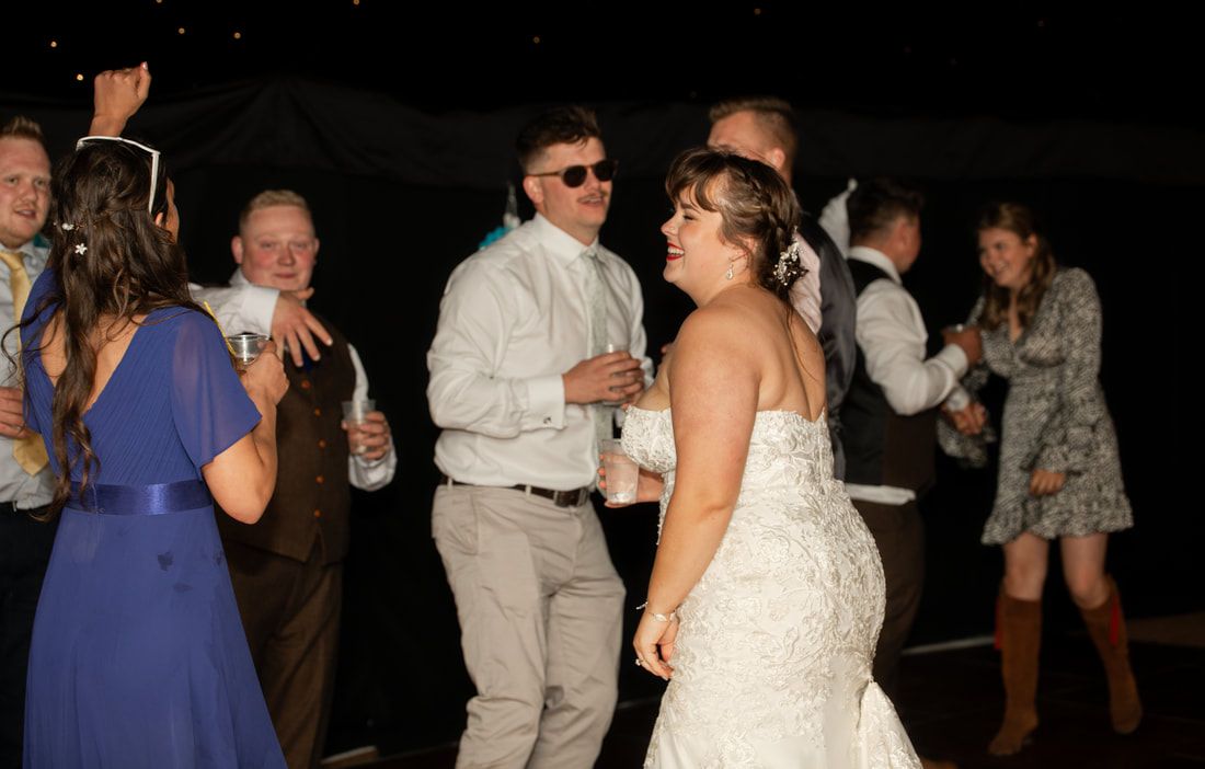 People dancing and socializing at a dimly lit wedding reception party.