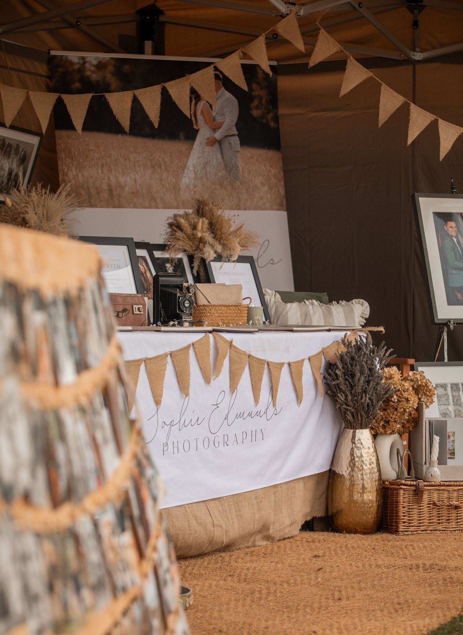 Rustic wedding photography booth with burlap bunting, dried florals, gold vases, and a Sophie Elaines Photography banner display.