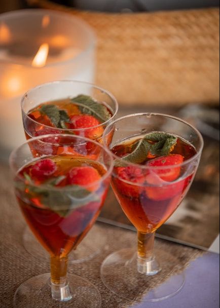 Two elegant martini glasses filled with a vibrant red cocktail garnished with fresh strawberries and mint leaves.