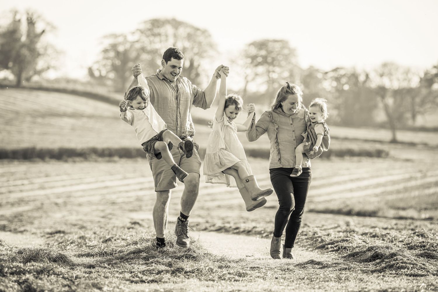 A family walks together through a misty field in black and white.