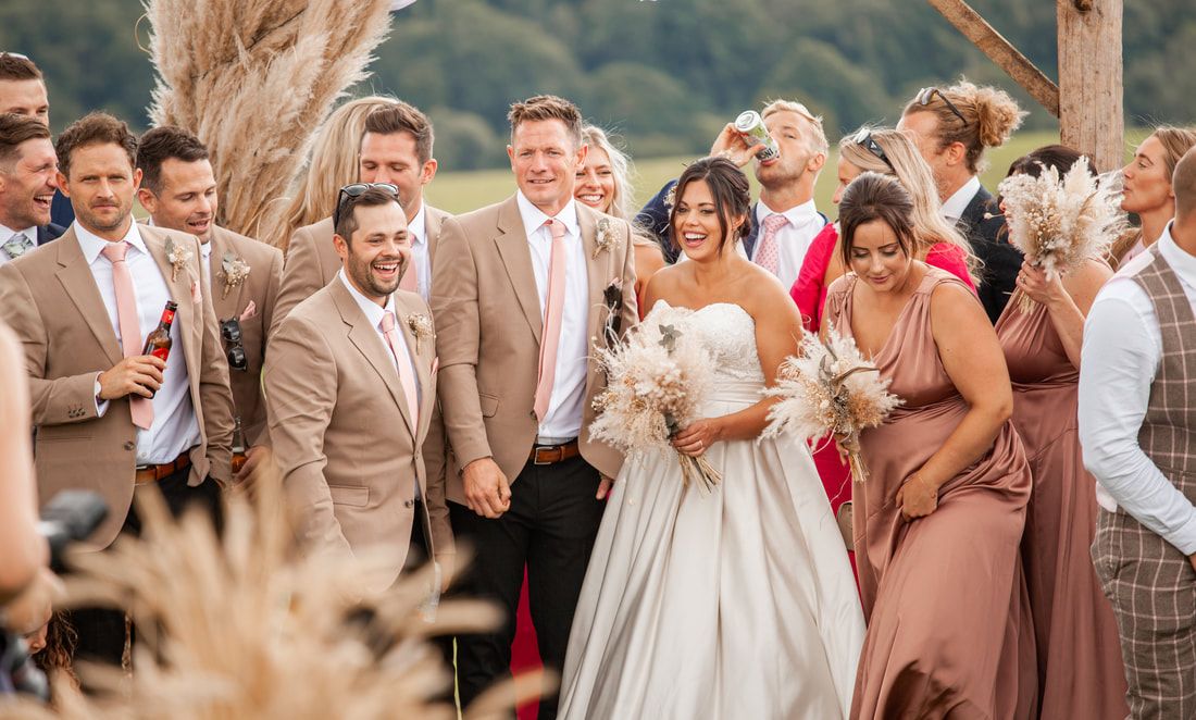 Wedding guests share joyful laughter during an outdoor celebration at golden hour.