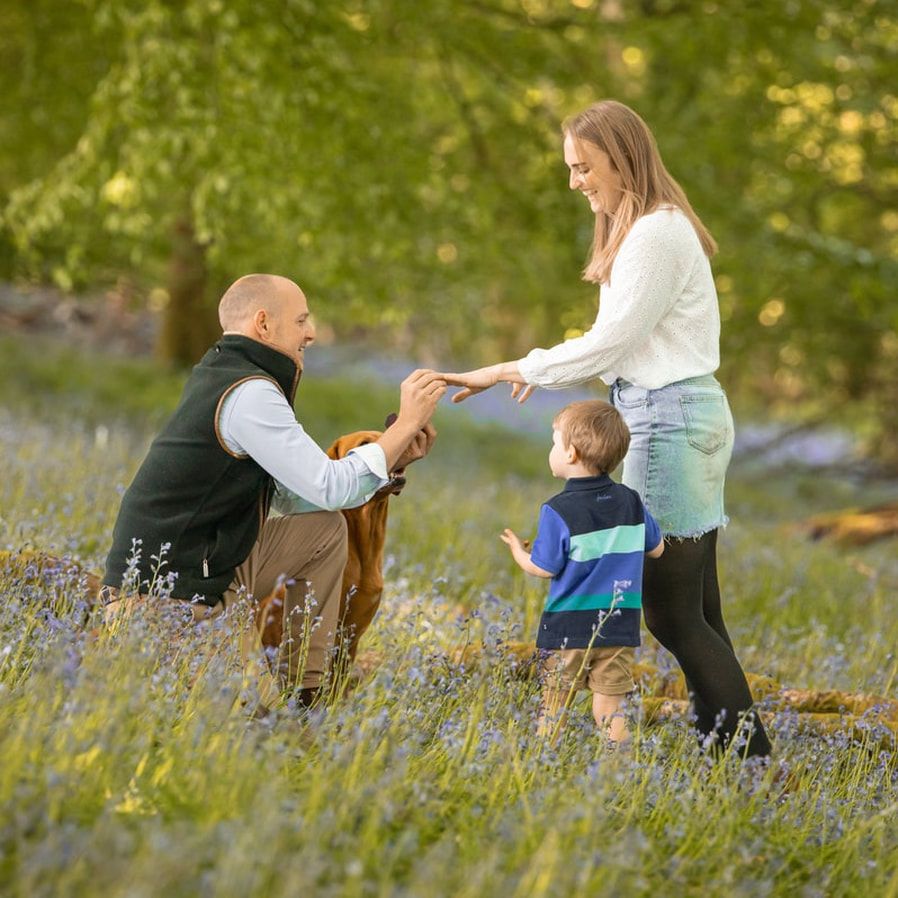 Family enjoying a tender moment together while sitting in a wildflower meadow on a sunny afternoon.