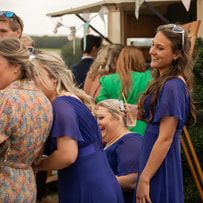 Group of people gathered outdoors in casual attire having animated conversations at a social event.
