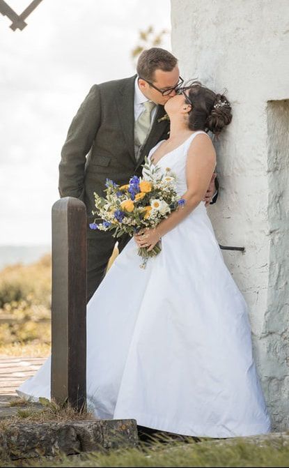 Romantic wedding couple shares intimate moments against a rustic white wall in a series of tender photographs.