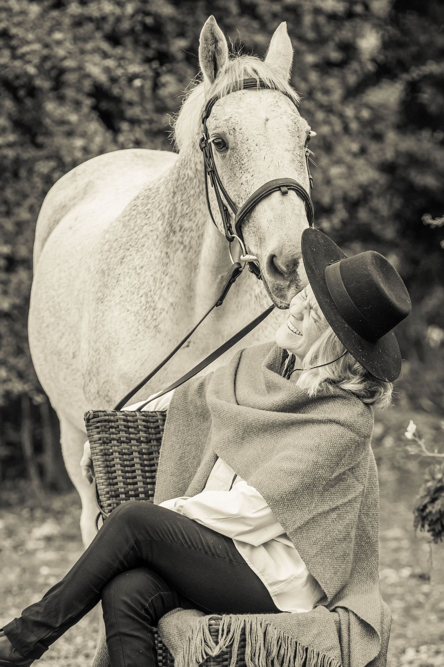 Black and white photo series showing a person in dark clothing interacting affectionately with a white horse in nature.