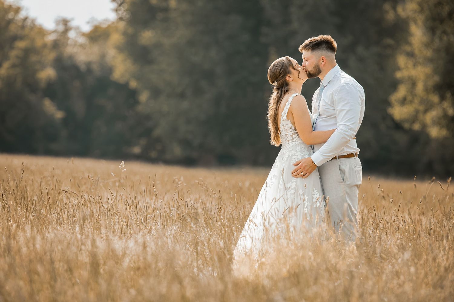 A romantic wedding couple embraces in a golden hay field during sunset at outdoor wedding venue Walnut Barn Estate.