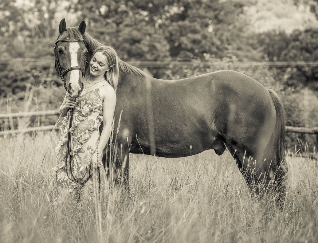 A black and white photo series showing a person in a flowing dress standing in a meadow with a horse.