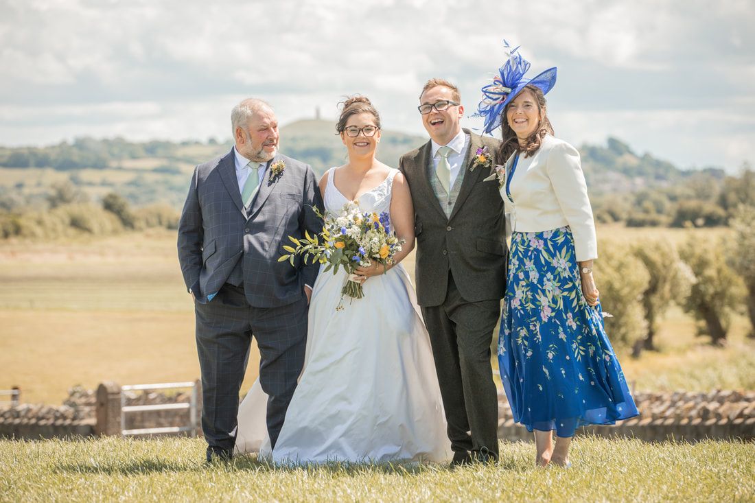 Wedding party poses together on a scenic hilltop overlooking a beautiful countryside landscape.