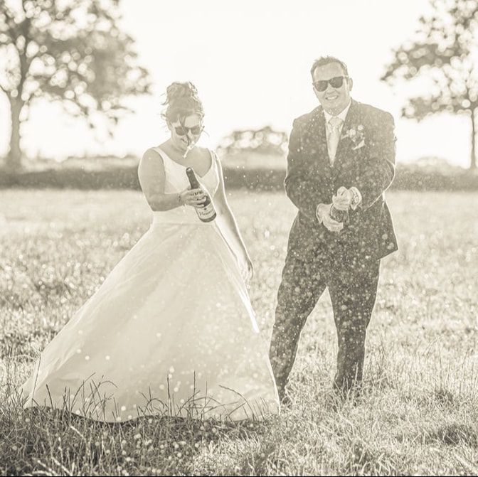Black and white wedding couple playfully running through a sunlit meadow in romantic photo sequence.