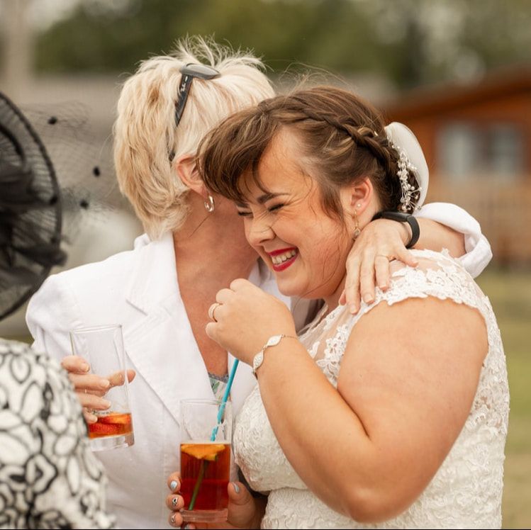 Two people share an intimate moment of laughter and joy while sitting together at a table with drinks.