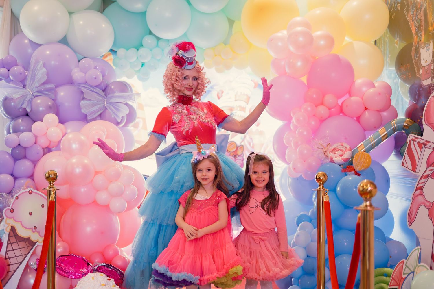 A fairy-themed celebration with pastel balloon arches and performers in colorful dresses.
