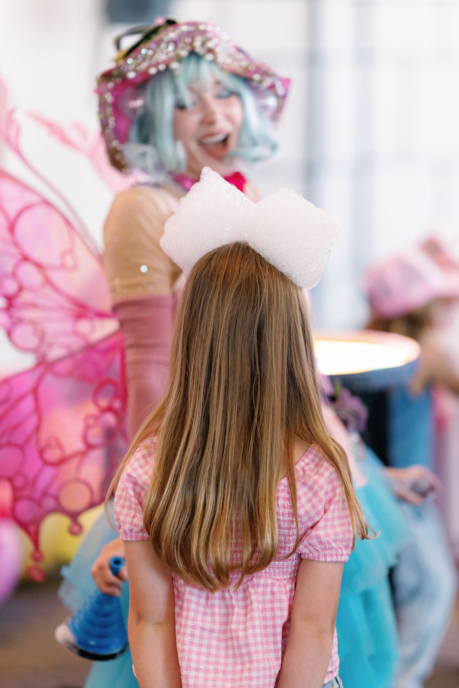 Party scene with pink gingham dress and magical entertainment performance.