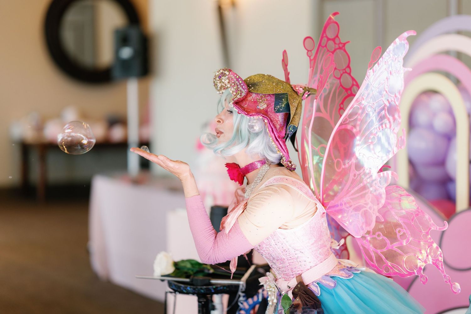 Pink butterfly decorations and string lights create a magical party atmosphere.