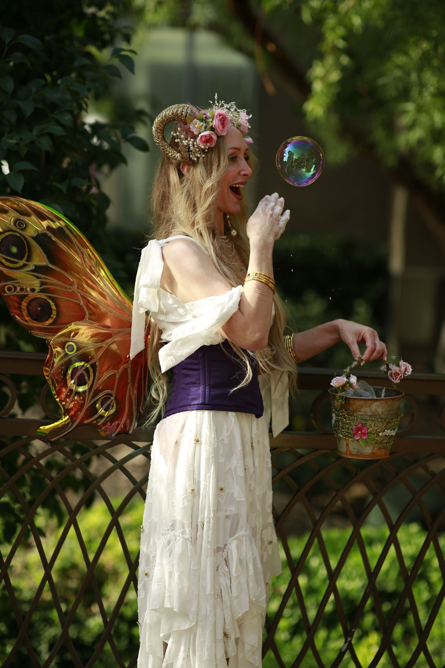 Fairy-themed outdoor photoshoot with bubbles and fantasy costume elements in a garden setting.