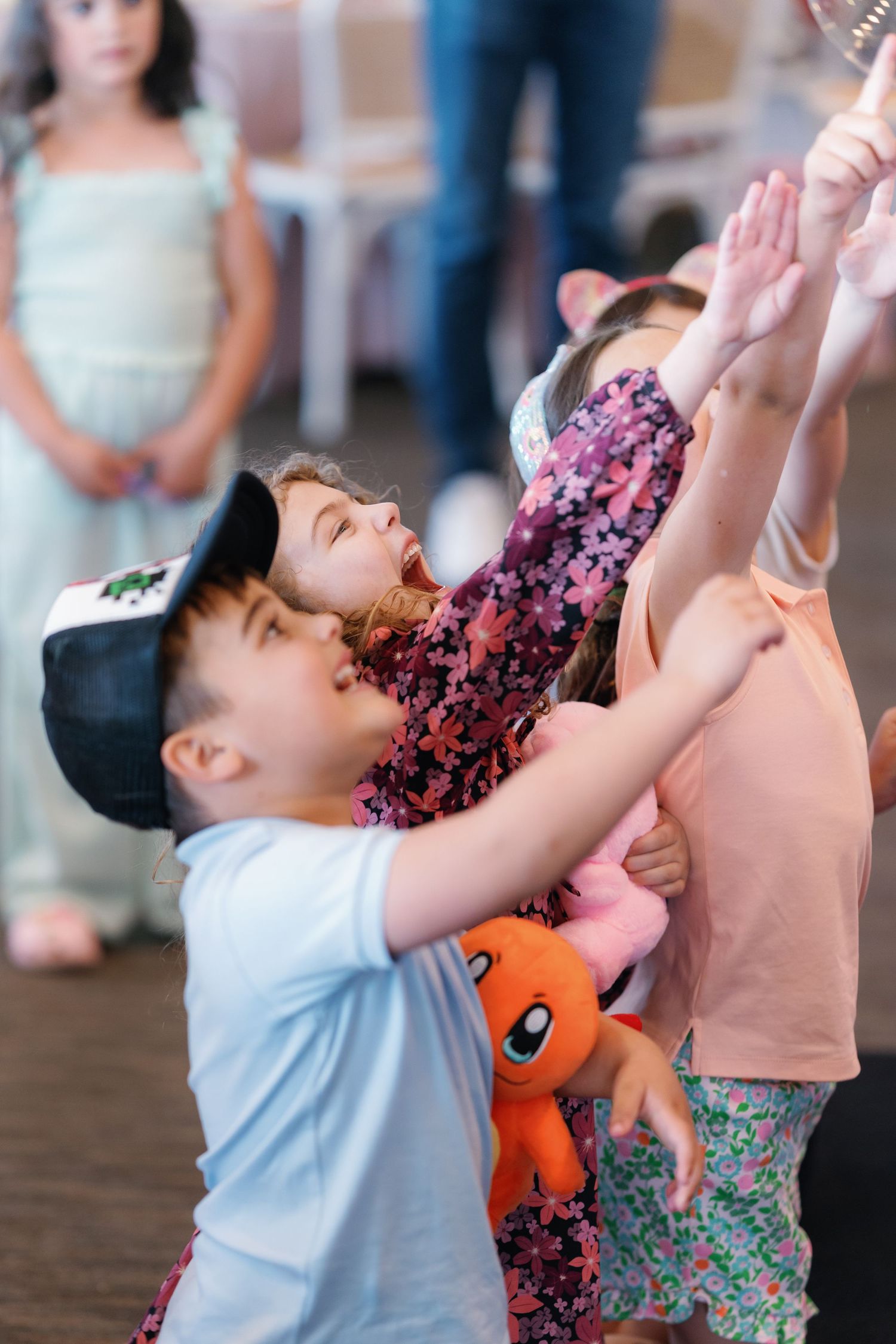 Children playing and reaching up during an interactive party performance.