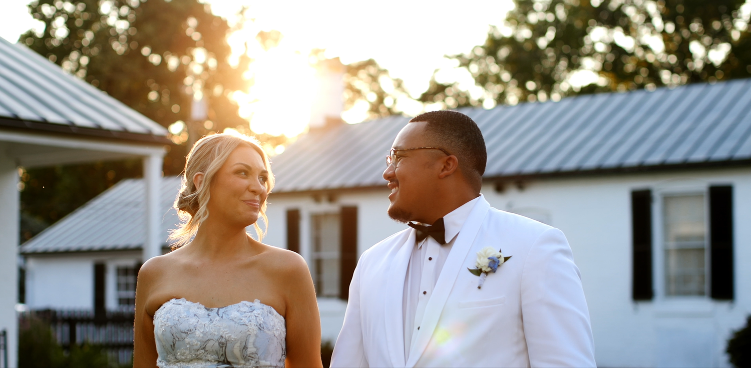 A couple in formal wedding attire standing together during golden hour.