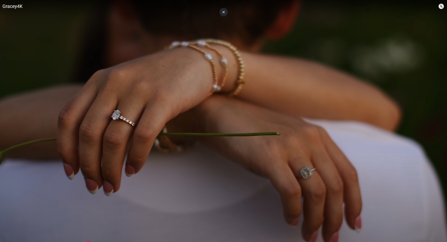 Close-up of hands with rings resting on white fabric.