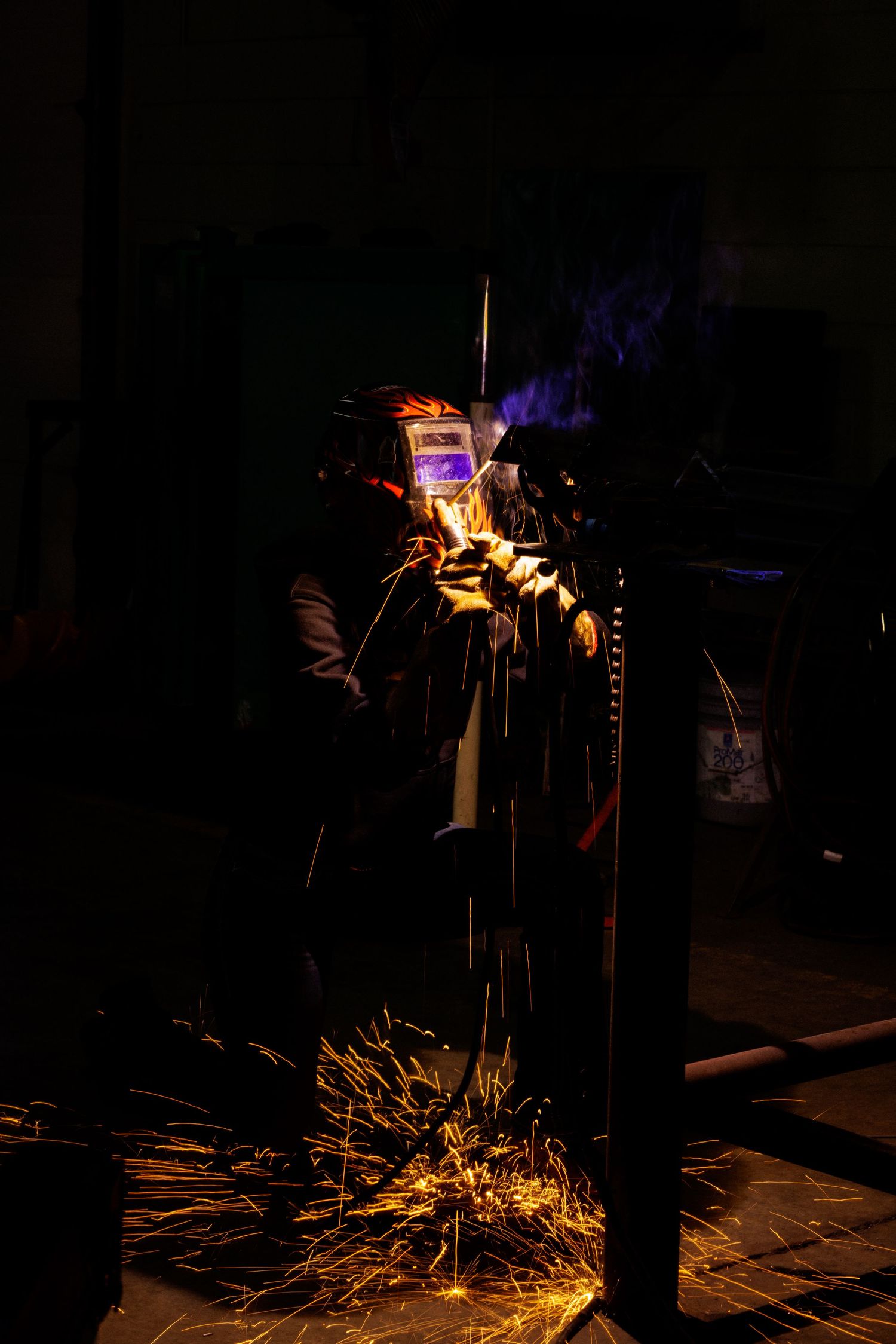 Welder working at night with bright sparks flying during metal fabrication process.