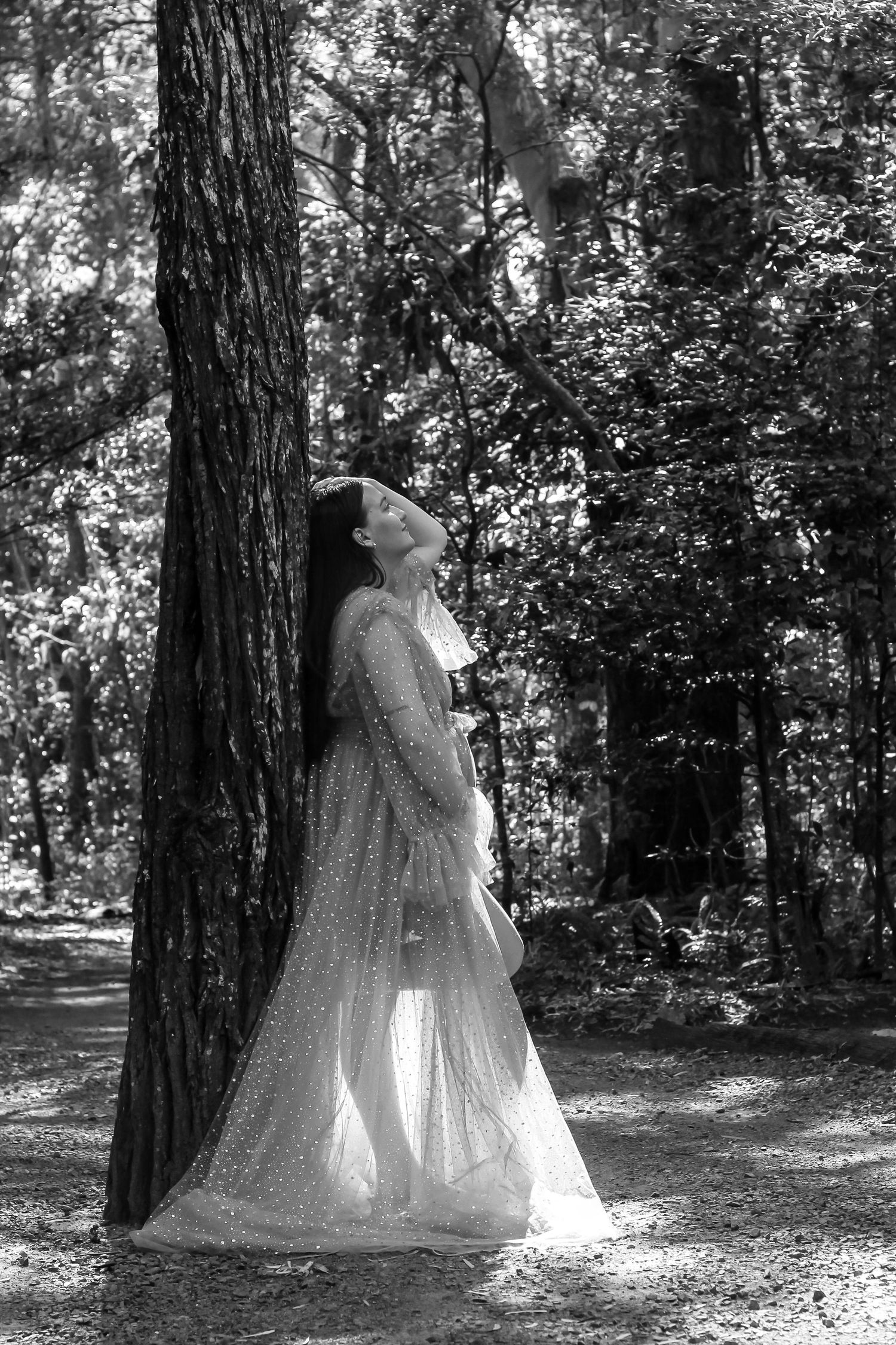 Pregnant mother standing in next to a tree in the morning, maternity photography session in Hervey Bay.