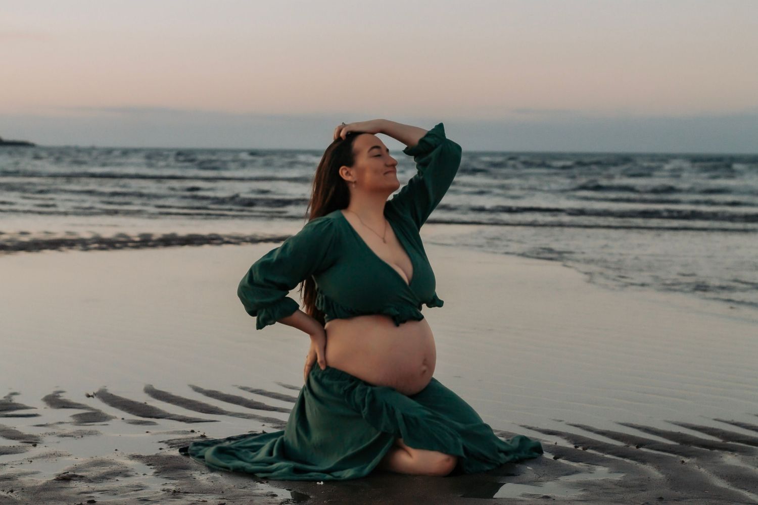 Pregnant mother laying in the low tide during sunset maternity photography session in Hervey Bay.