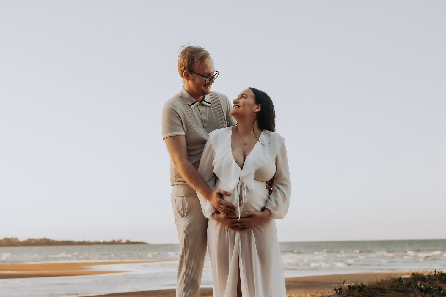 Mother to be and Father to be cuddling their first baby bump during a relaxed outdoor motherhood photography session in Hervey Bay.