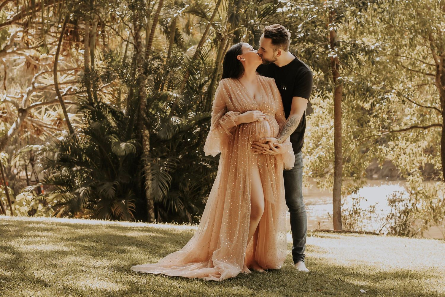 Mother to be and Father to be cuddling their first baby bump during a relaxed outdoor motherhood photography session in Hervey Bay.