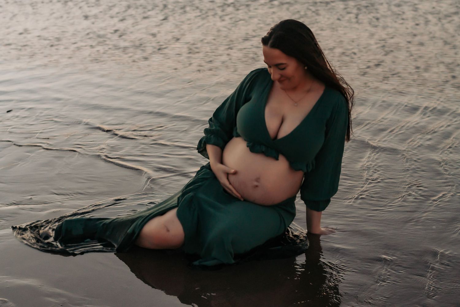 Pregnant mother laying in the low tide during sunset maternity photography session in Hervey Bay.