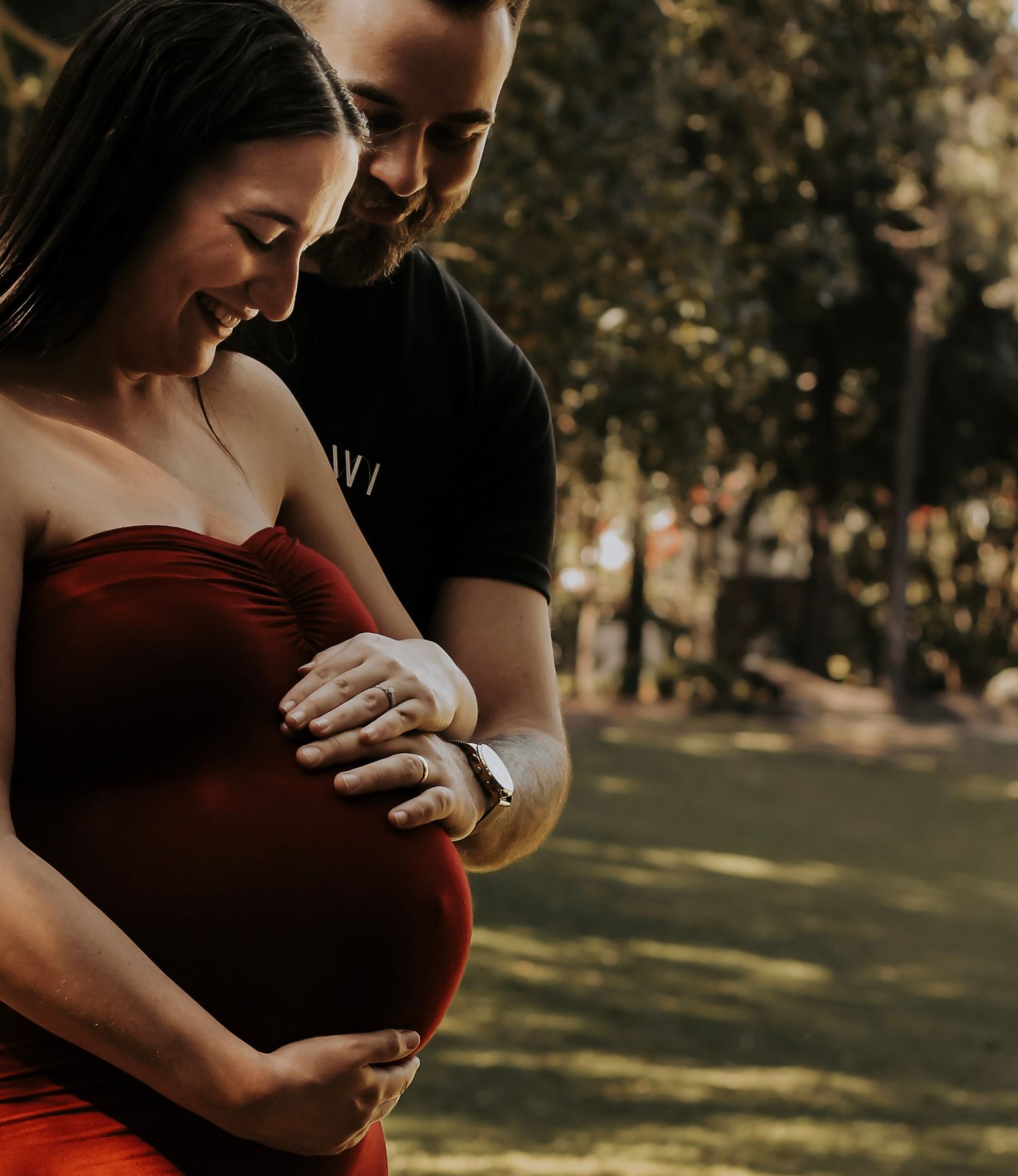 Mother to be and Father to be cuddling their first baby bump during a relaxed outdoor motherhood photography session in Hervey Bay.