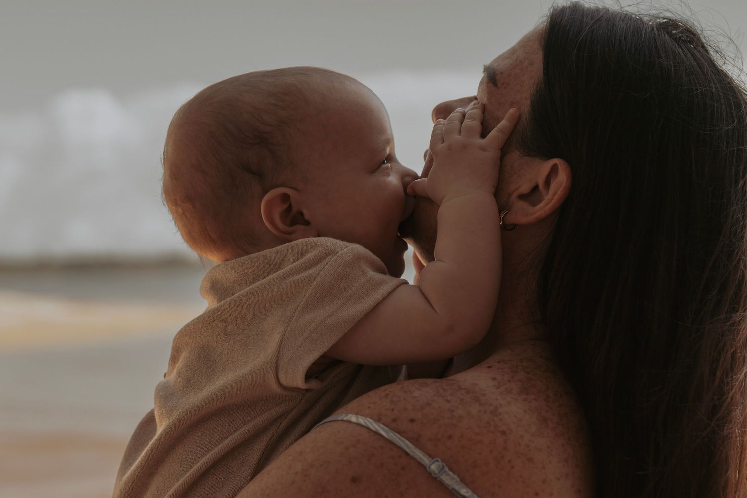 Baby getting Mum cuddles at the beach in the morning. Motherhood Photographer