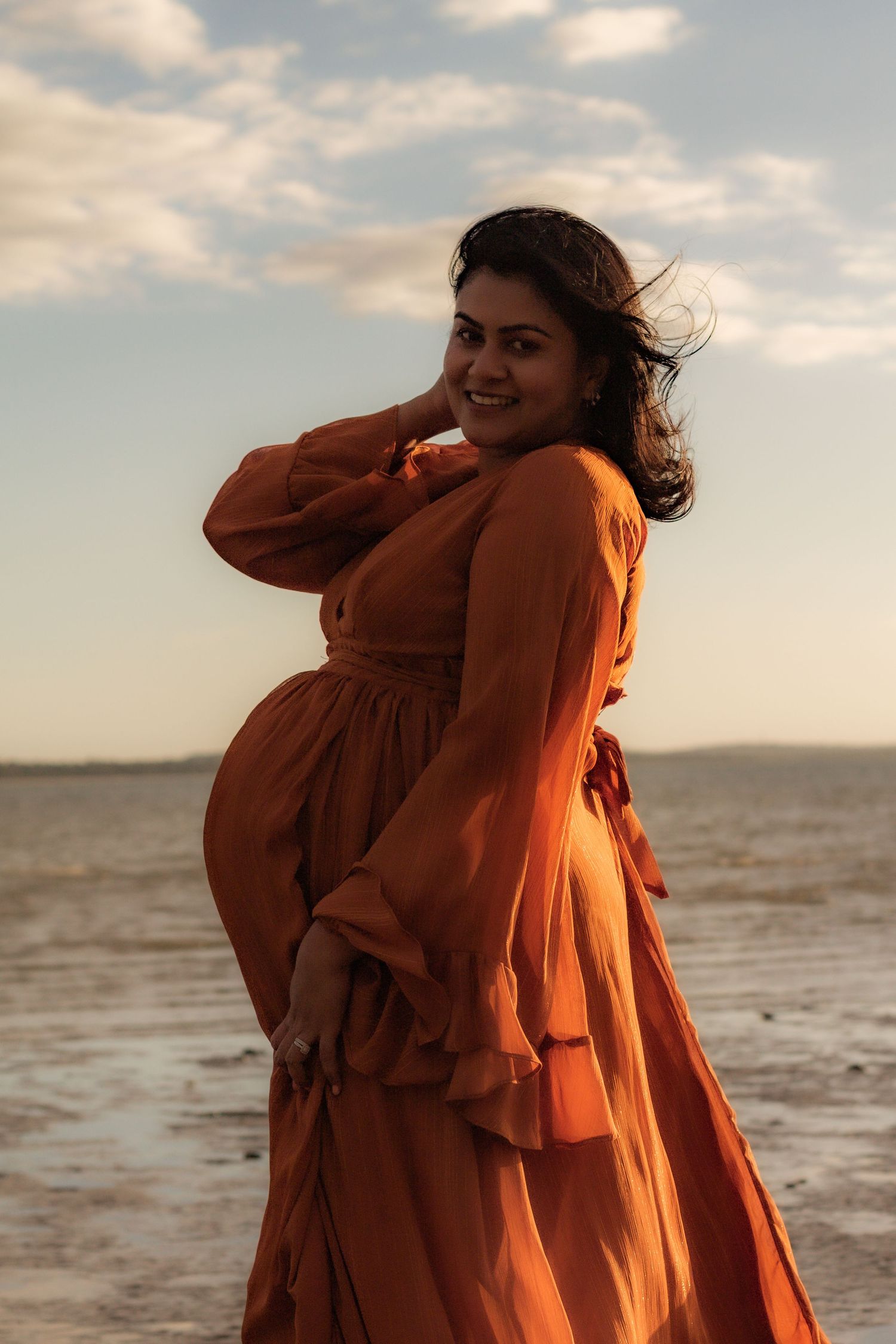 Expecting mother standing at the beach in a beautiful sunset maternity session in Hervey Bay.