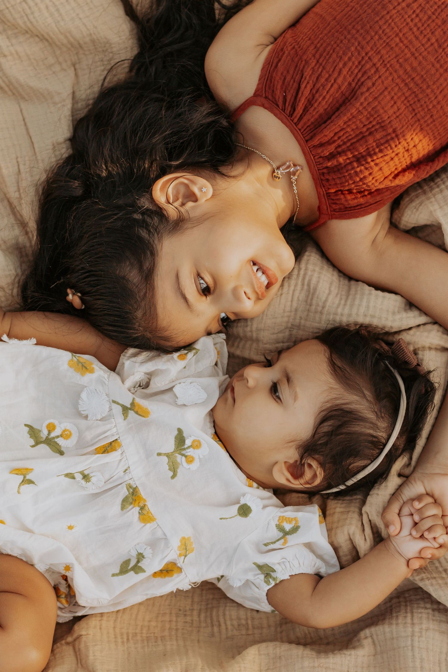 Two siblings laying down together in a field during a sunset family photography session in Hervey Bay.